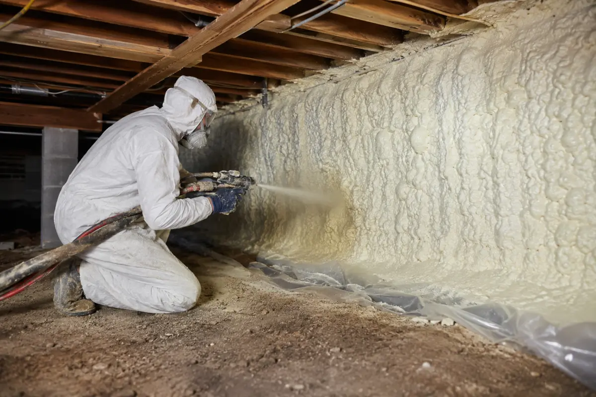 Installer applying spray foam to a crawlspace foundation wall