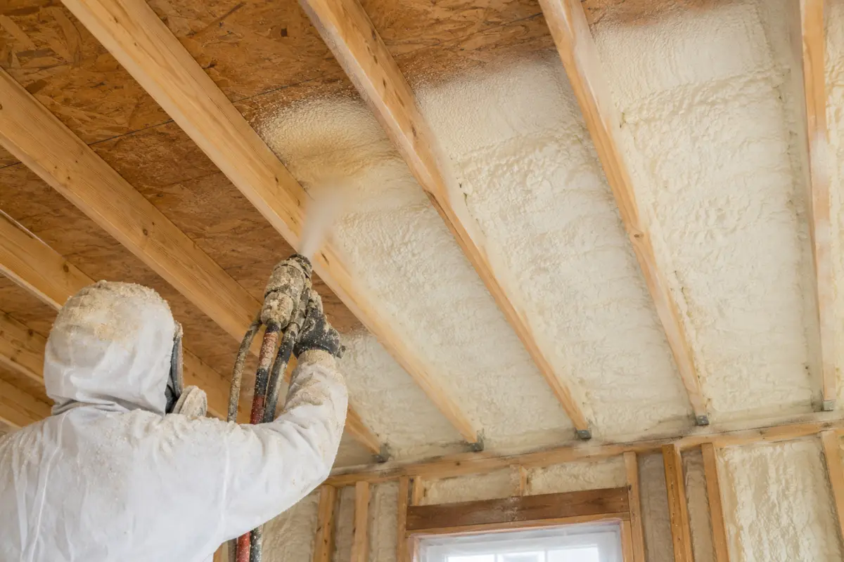 Installer applying spray foam between timber roof rafters