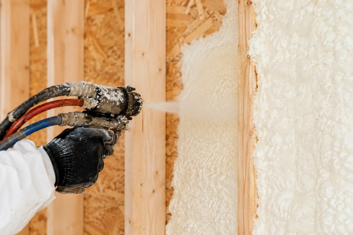 Close view of a spray foam gun filling a framed wall cavity