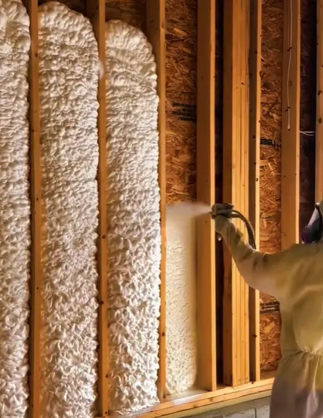 Spray foam being applied in tall wood-framed wall cavities